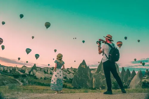 Man taking photo of woman and hot air balloons