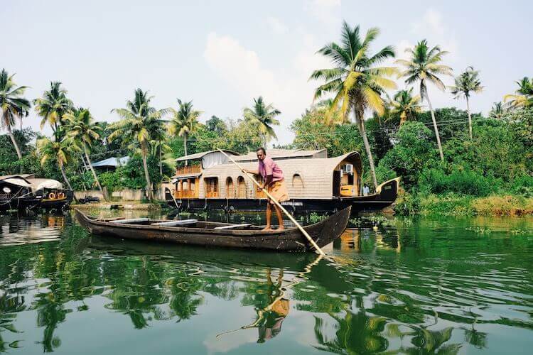 Kerala Backwaters, Alappuzha, India, man rowing boat in front of houseboat