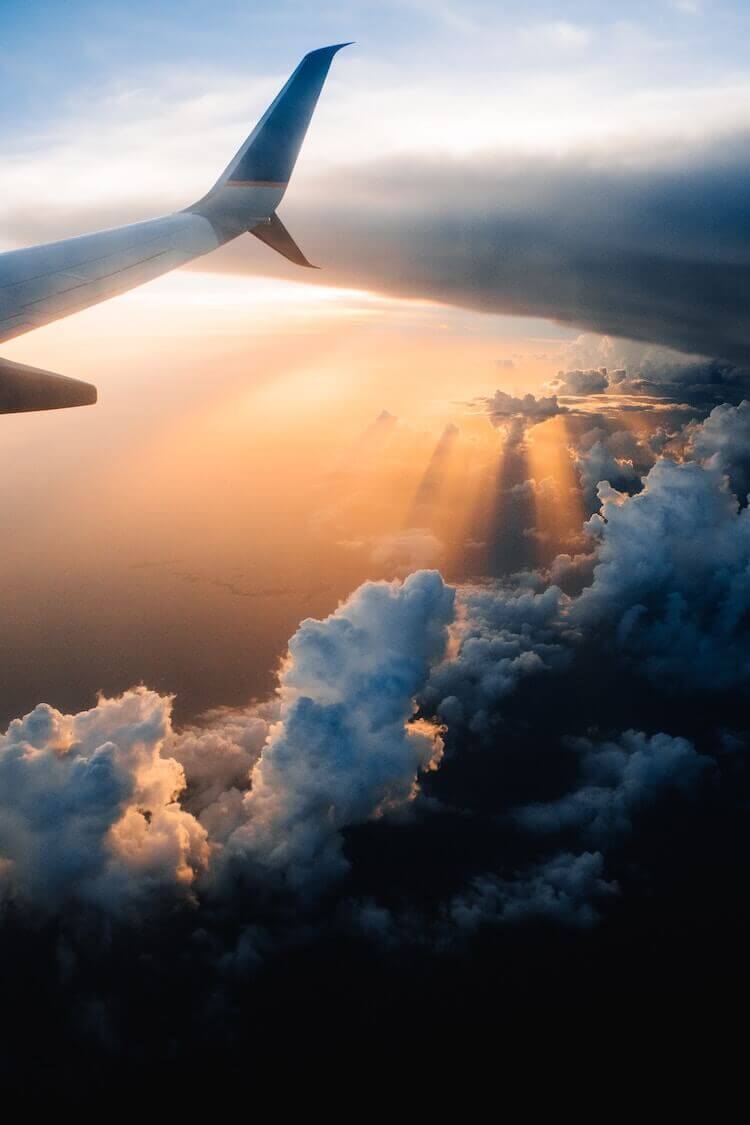 plane flying over clouds at sunset