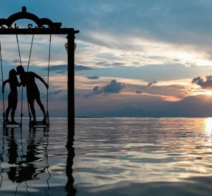 Couple kissing over ocean on swing