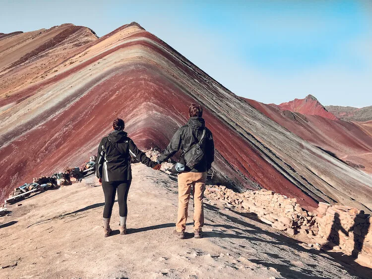 Kat and Chris standing in front of Rainbow Mountain facing it
