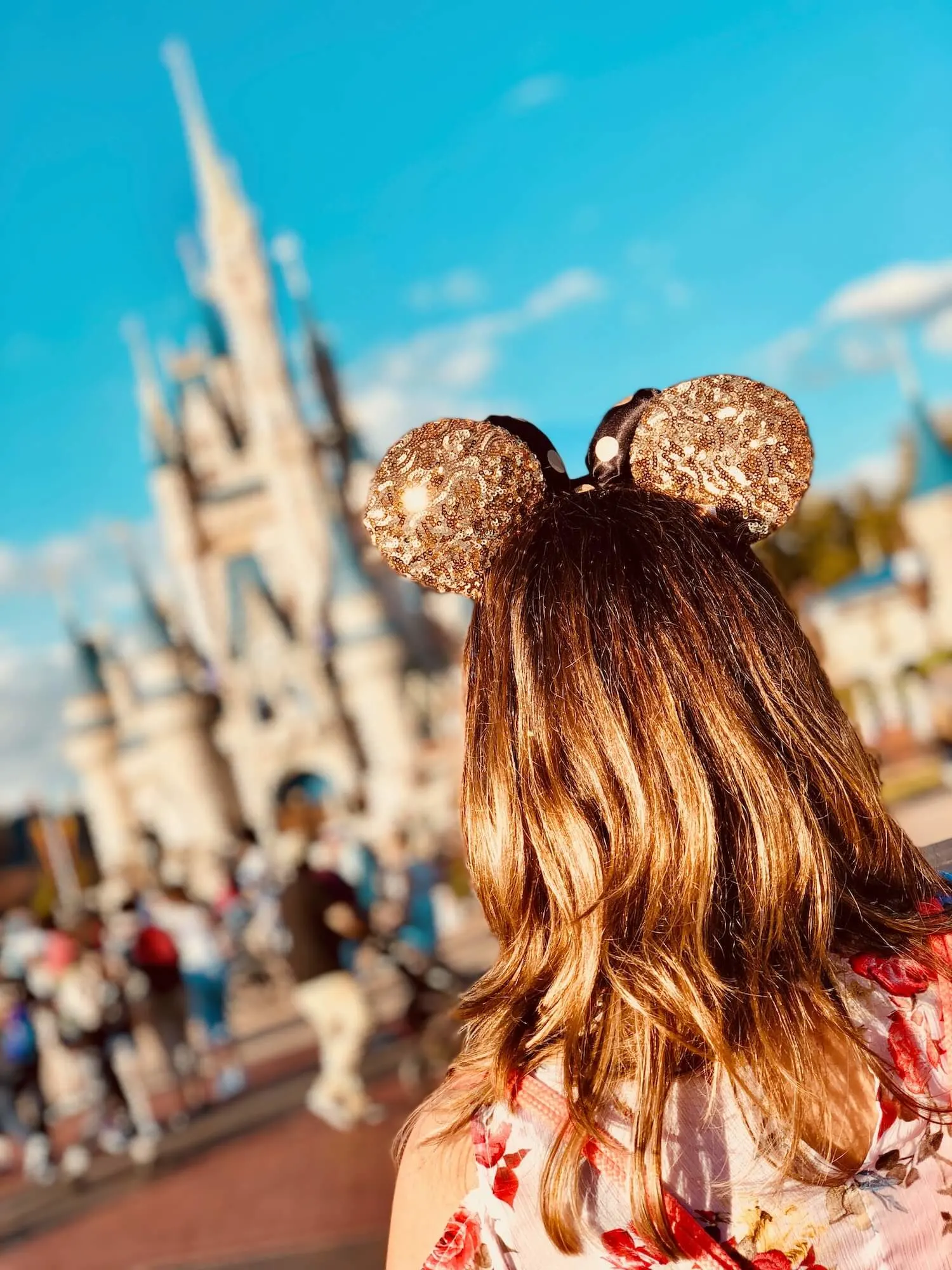 Girl with gold Disney ears in front of Cinderella's Castle at Disney World