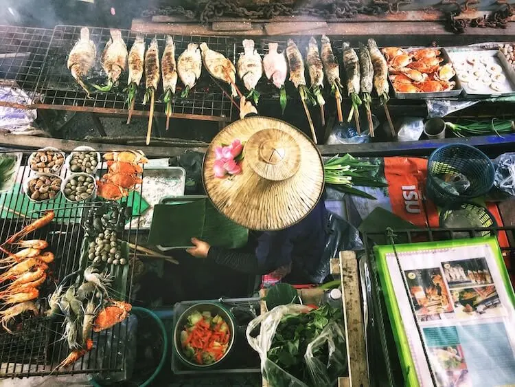 Woman grilling fish on a boat in Bangkok