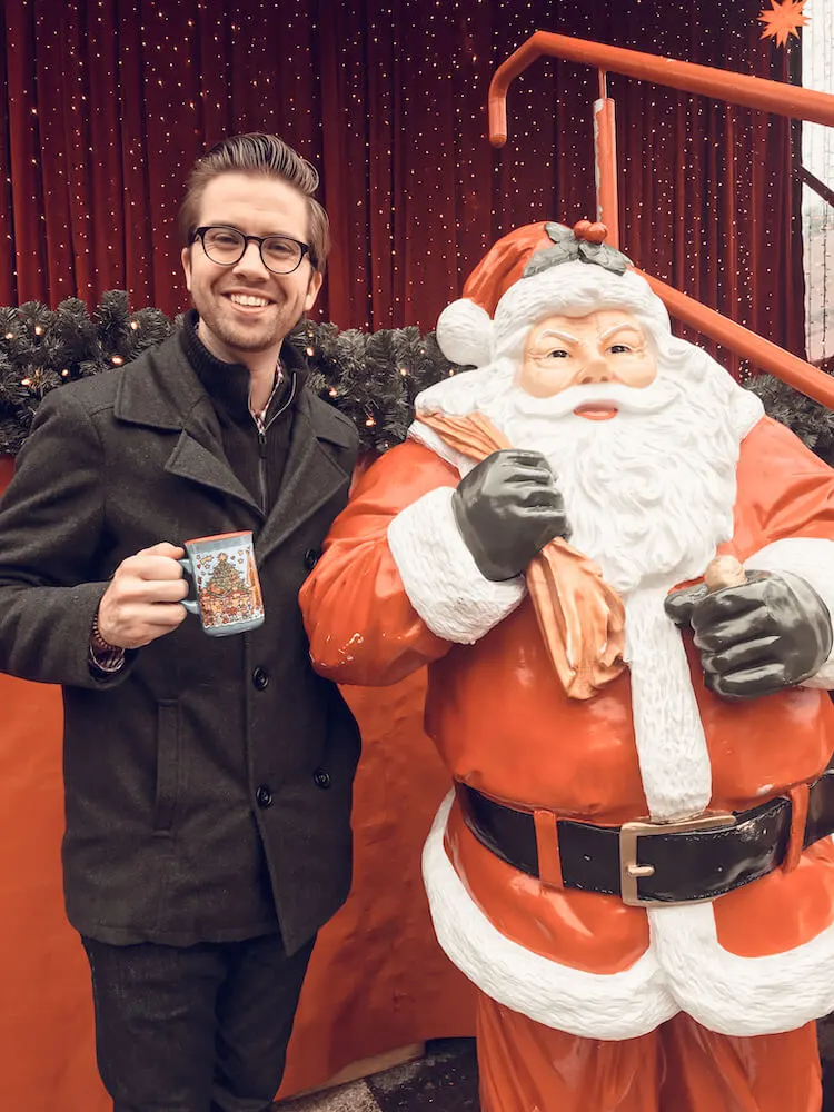 Chris at the Cologne Cathedral Christmas market posing with a lifesize Santa Claus statue