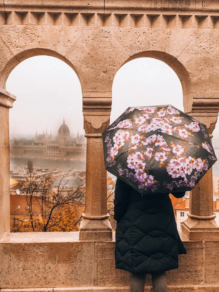 Kat looking out from Fisherman's Bastion in the rain toward the Hungarian Parliament Building