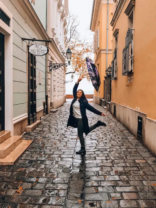 Kat twirling with a purple and black umbrella in a side street in Budapest, Hungary