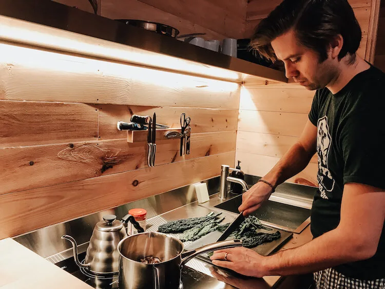 Chris preparing ramen by chopping kale using Getaway House's kitchen