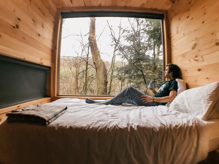 Chris sitting in the bed looking out of the window and drinking coffee in our weekend getaway in Ohio for couples