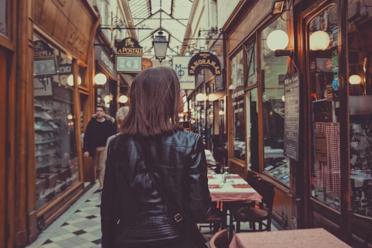 Girl wearing a black leather jacket in a covered market in Paris- What to Wear in Paris