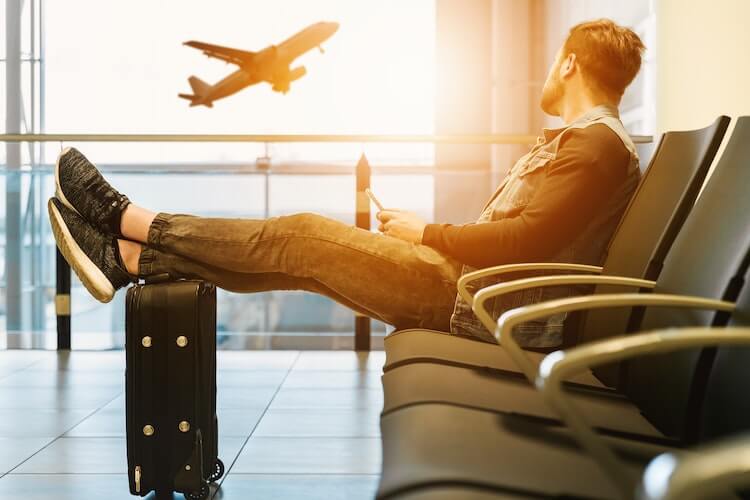 Man sitting at the airport looking at a plane outside
