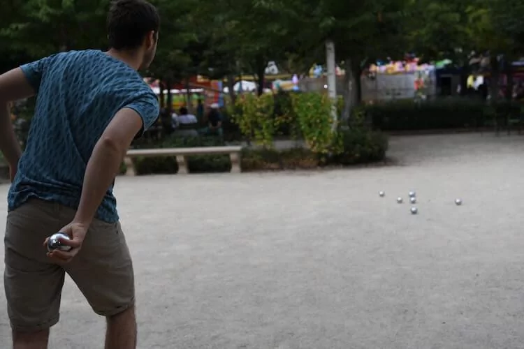 Man wearing a blue t-shirt and shorts playing in a park in Paris