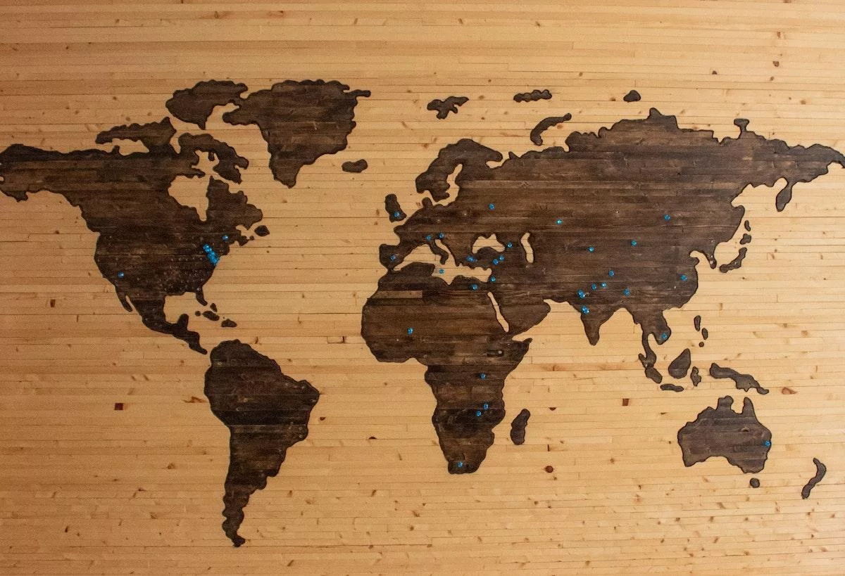 Pins on a wooden world map- how to travel while at home