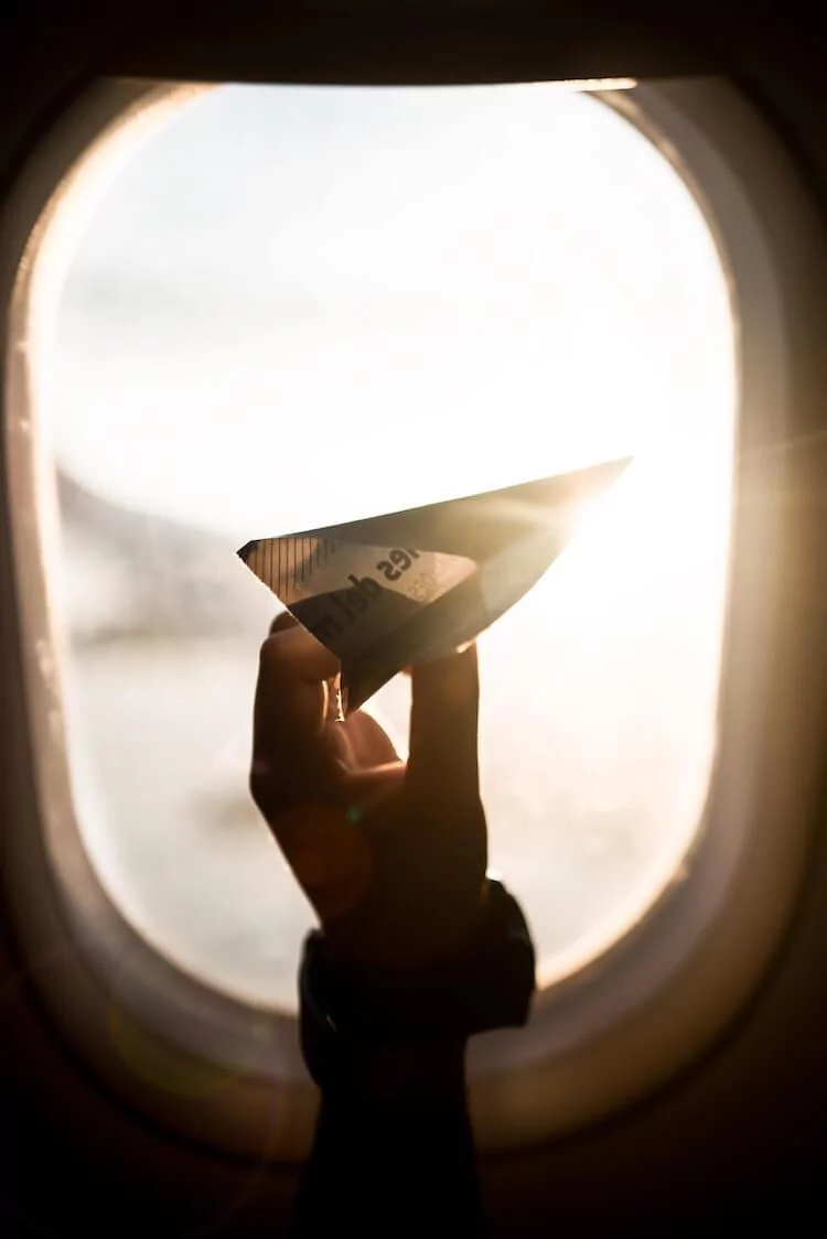 paper airplane next to a airplane window