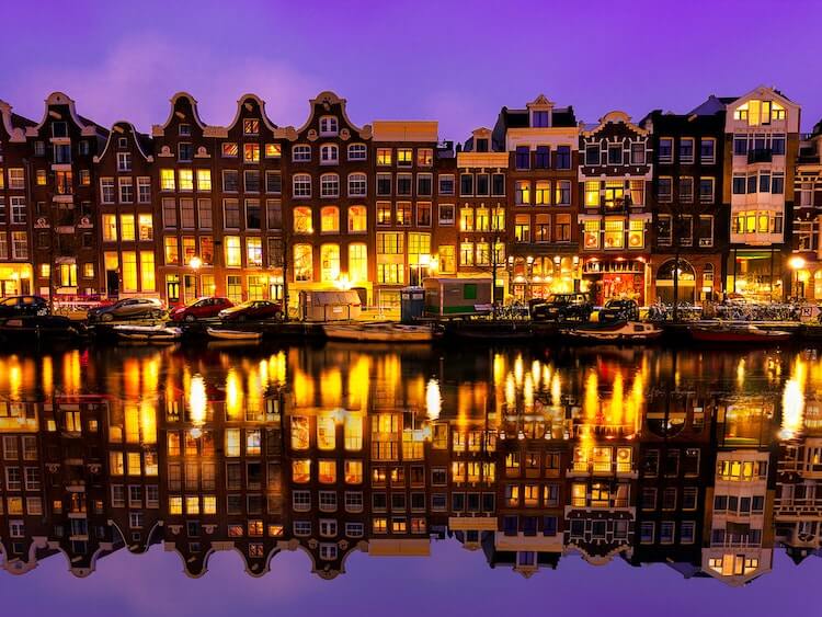 Amsterdam at twilight with the houses lit and reflecting on the canal