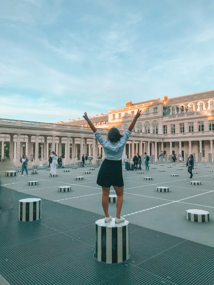 Kat on a pillar in Paris with a black dress with a white button down