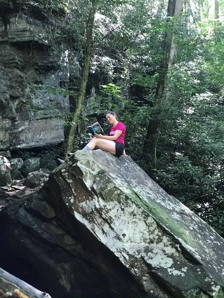 Kat reading the Moon Travel Guide to the Great Smoky Mountains National Park on a rock