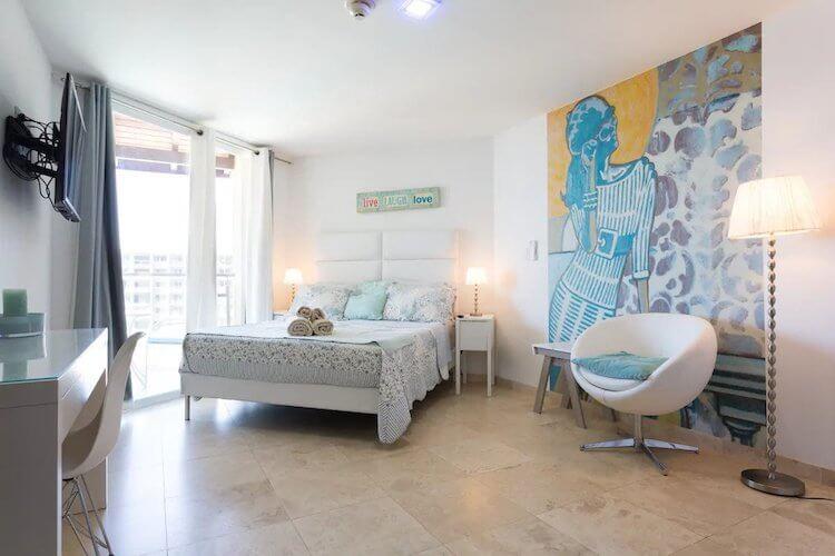 Aruba Airbnb room with yellow, blue, and gray artwork on the wall