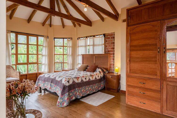 Sacred Valley, Peru Airbnb - Bedroom with big windows, wood beams, and wooden wardrobe