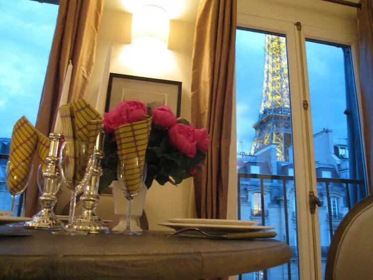 View of the Eiffel Tower Lit at Night from a Paris Honeymoon Airbnb with roses on the table