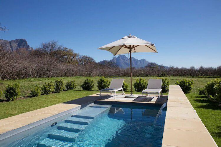 Winelands in South Africa with pool and umbrella in the foreground and mountains in the background