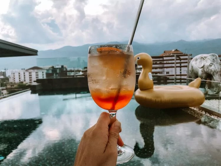 Rooftop pool hotel with a swan float in the background and aperol spritz in the foreground