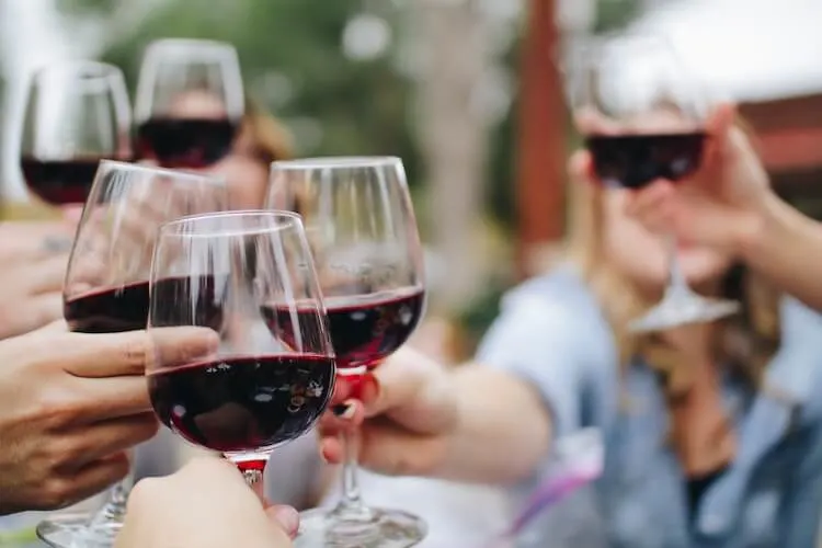 6 people holding up red wine in glasses