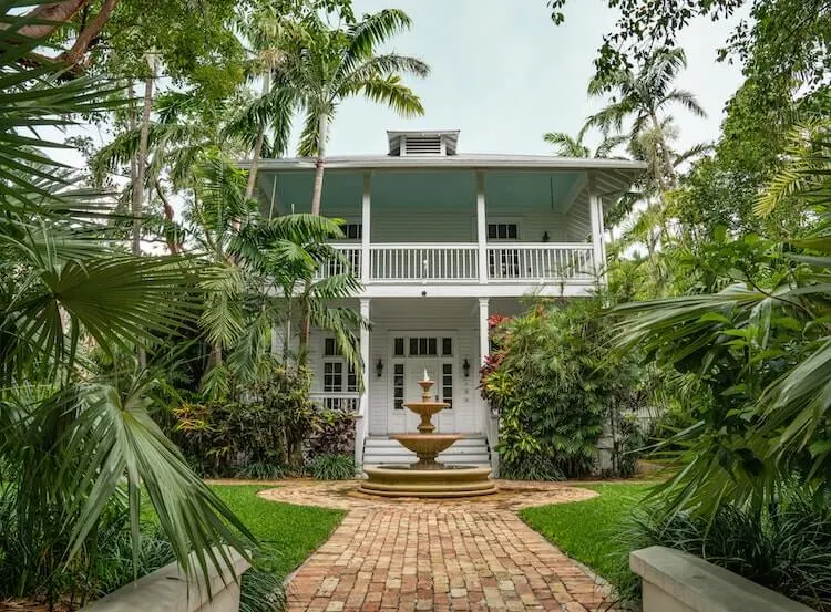 Charming house surrounded by palm trees and has fountain in the front in Key West