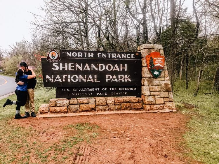 Kat and Chris kissing next to the north entrance of Shenandoah National Park