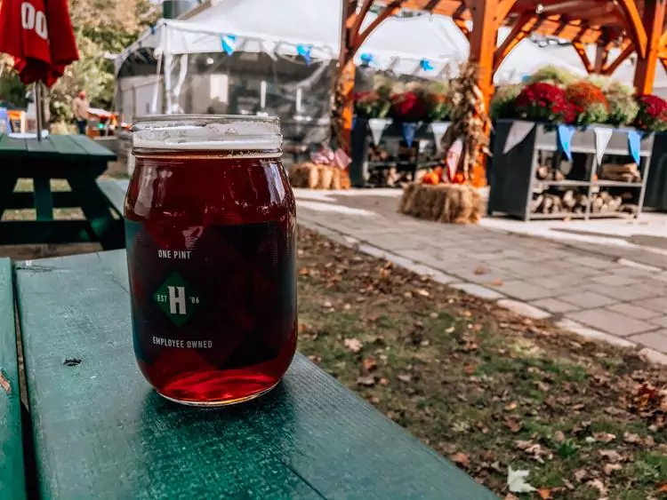 Mason jar glass full of amber ale on a green picnic table | Best Breweries in Vermont