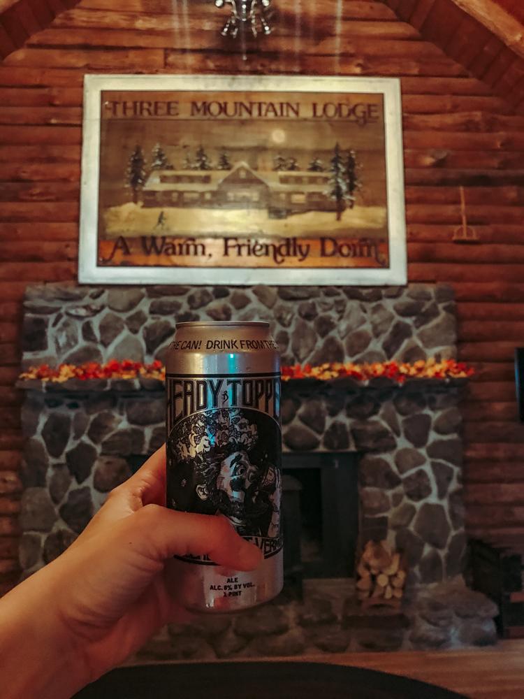 Vermont Beer Guide | Heady Topper can in front of a stone fireplace and three mountain lodge wooden sign