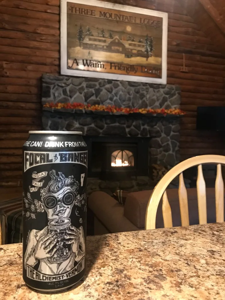 Where to drink beer in Vermont | Focal Banger on a counter in front of a stone fireplace with a wooden mountain lodge sign in the background