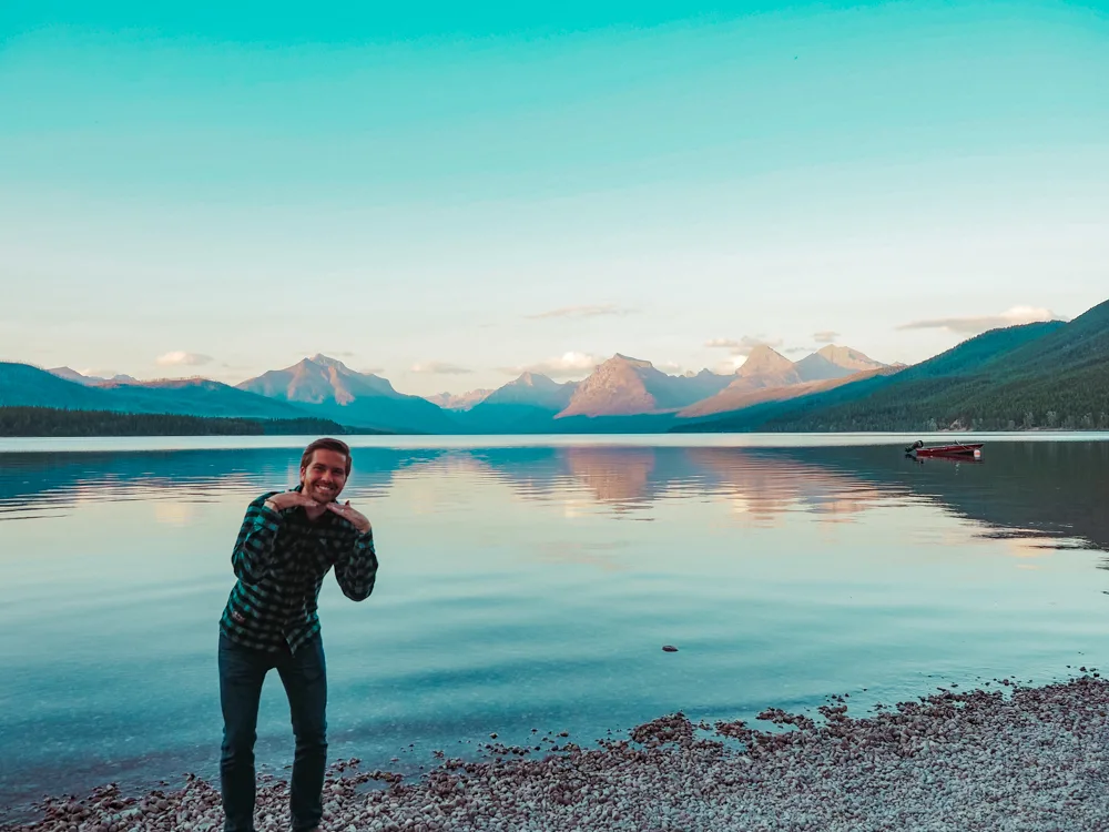 Chris posing with his hands no his chin facing downward in front of the lake at Lake McDonald