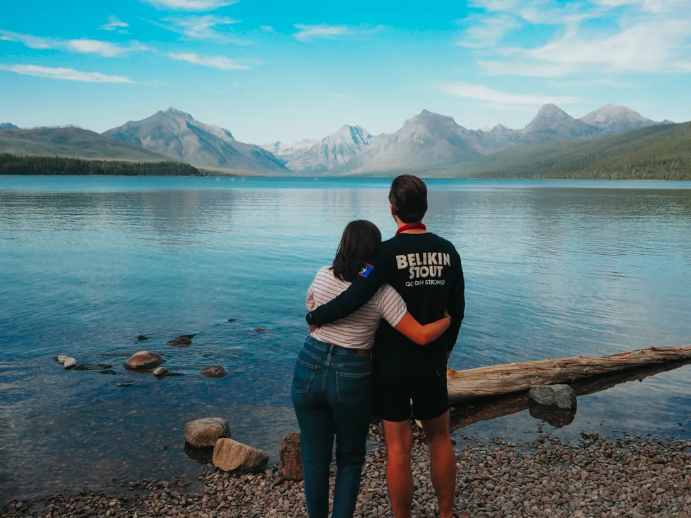 Kat and Chris cuddling with their arm around each other and looking over Lake McDonald | Itinerary Glacier National Park