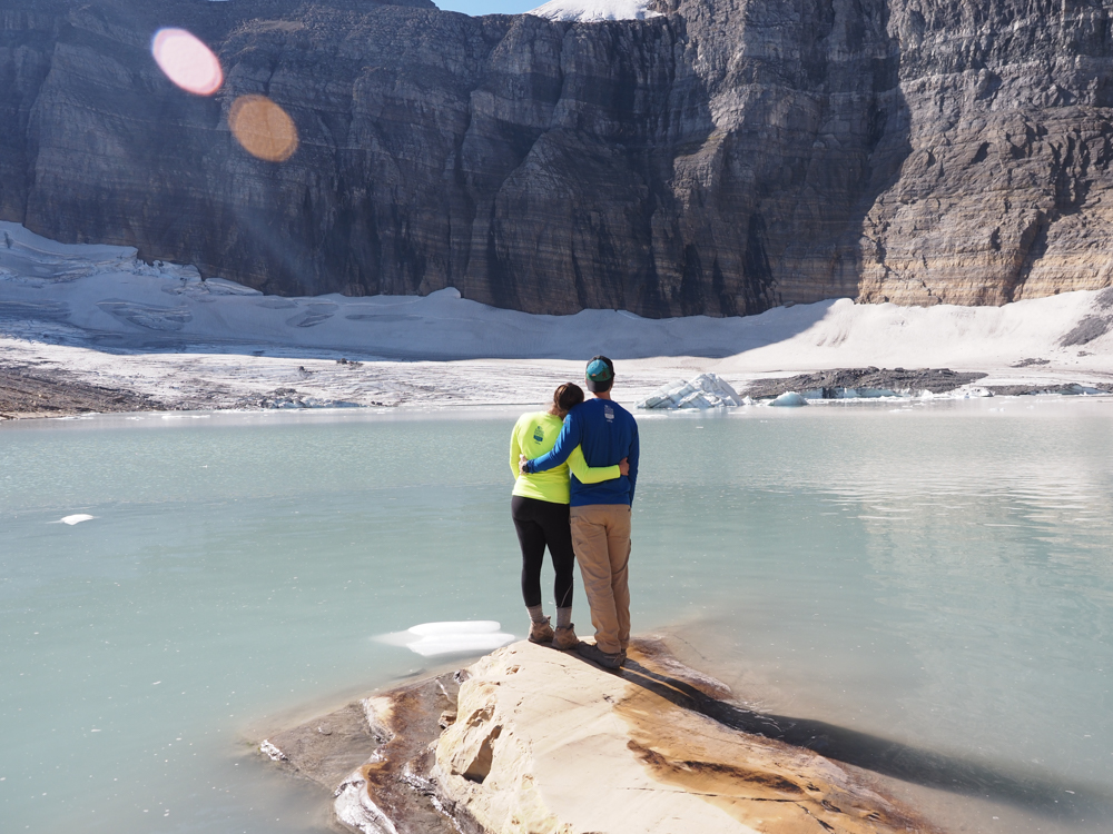 Kat and Chris embracing and looking at Grinnell Glacier while standing on a rock