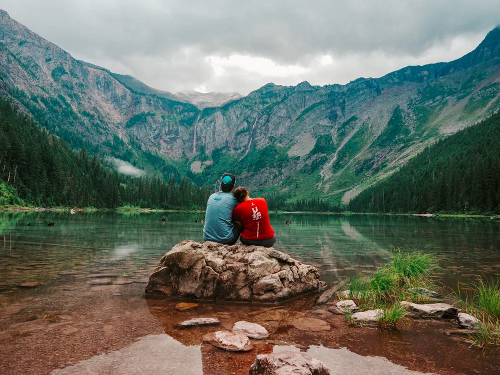 Kat and Chris sitting on a rock looking out over Avalanche Lake