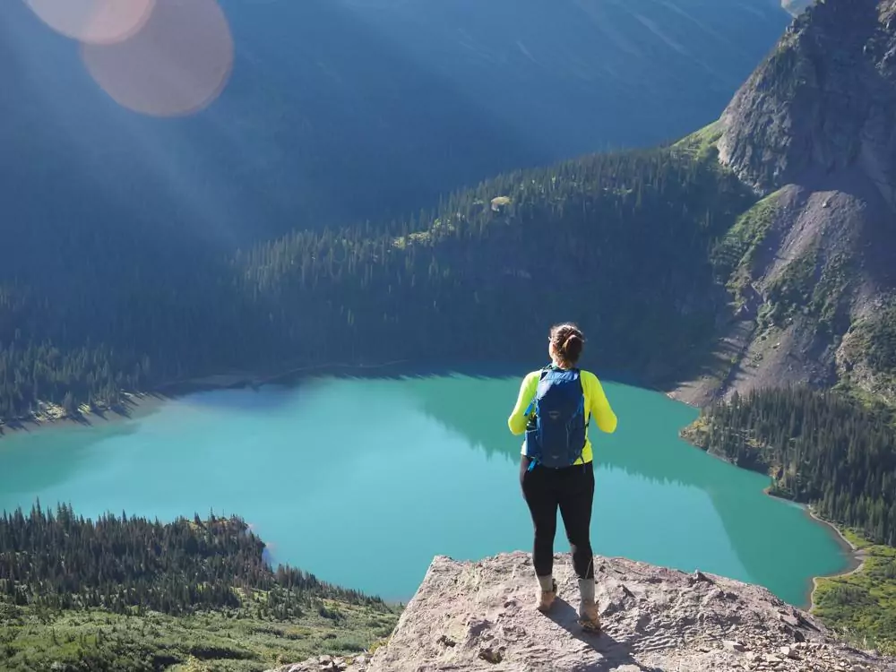 Kat wearing a blue backpack and looking at Grinnell Lake