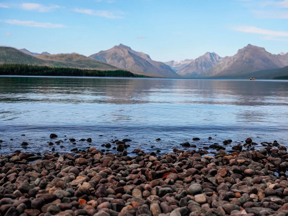 Rocky lakeshore of Lake McDonald with mountains in the background | Glacier National Park 7 Day Itinerary