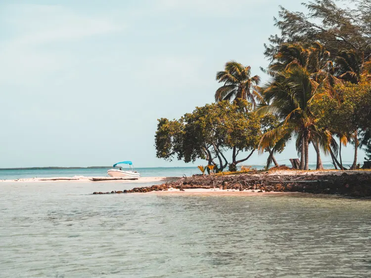 Beautiful beach in Belize on an island with boat on sand - Belize itinerary