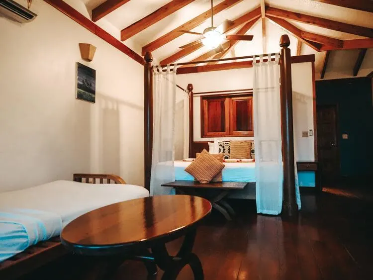 Bedroom with wood beams on ceilings, king bed, futon, coffee table, and fan