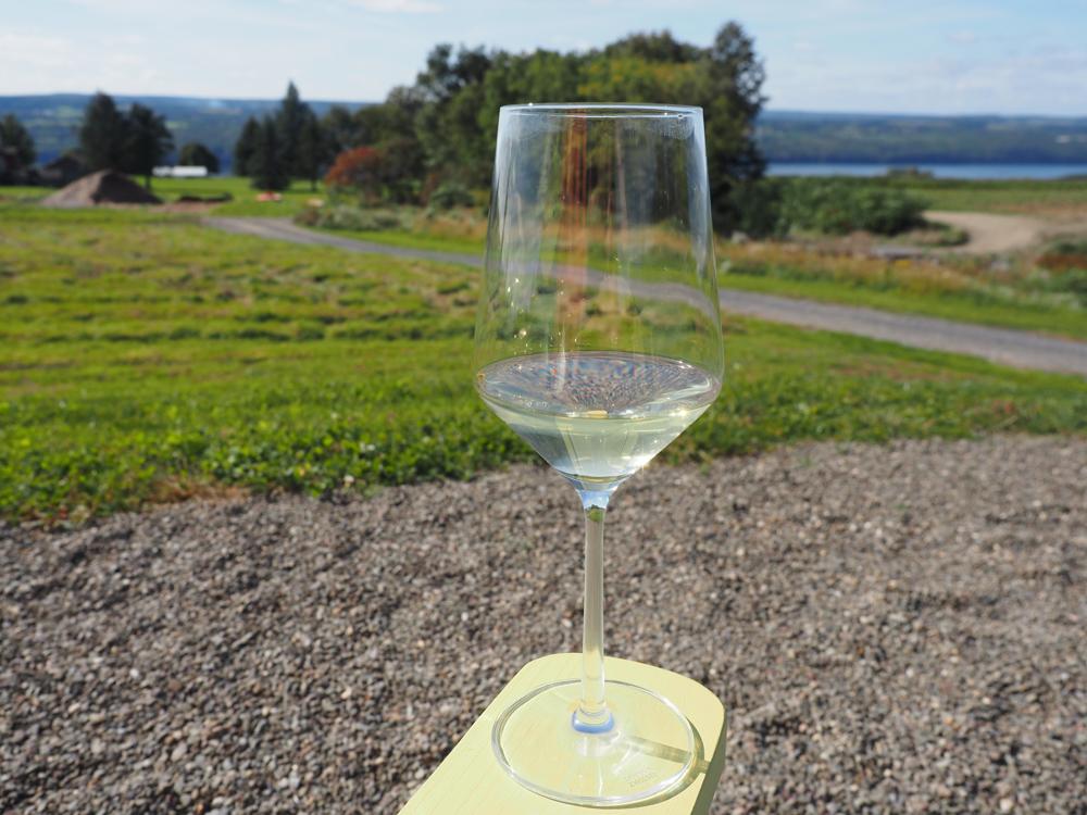 Forge Cellars white wine glass sitting on a yellow arm of a chair | Seneca Lake Wineries