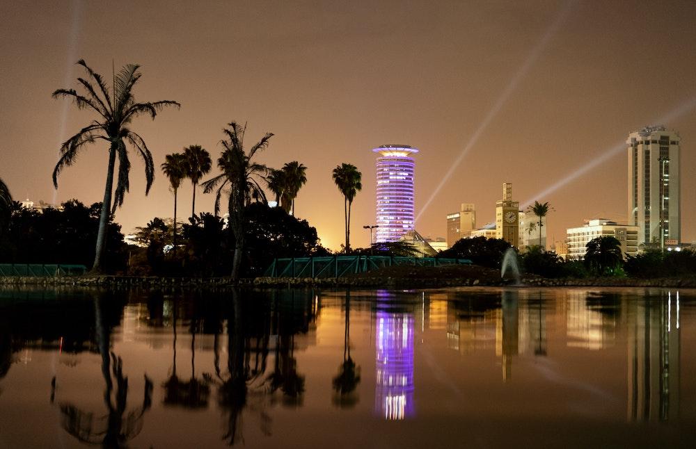 Nairobi at night with palm trees and a lake and buildings lit up