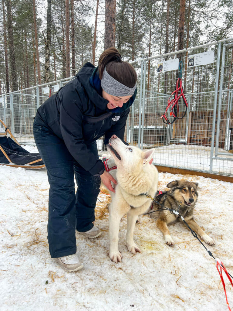 Kat petting a dog after dog sledding