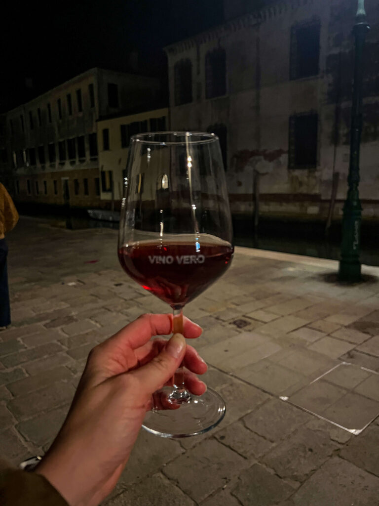 Glass of red wine with Vino Vero written on it being held by a hand