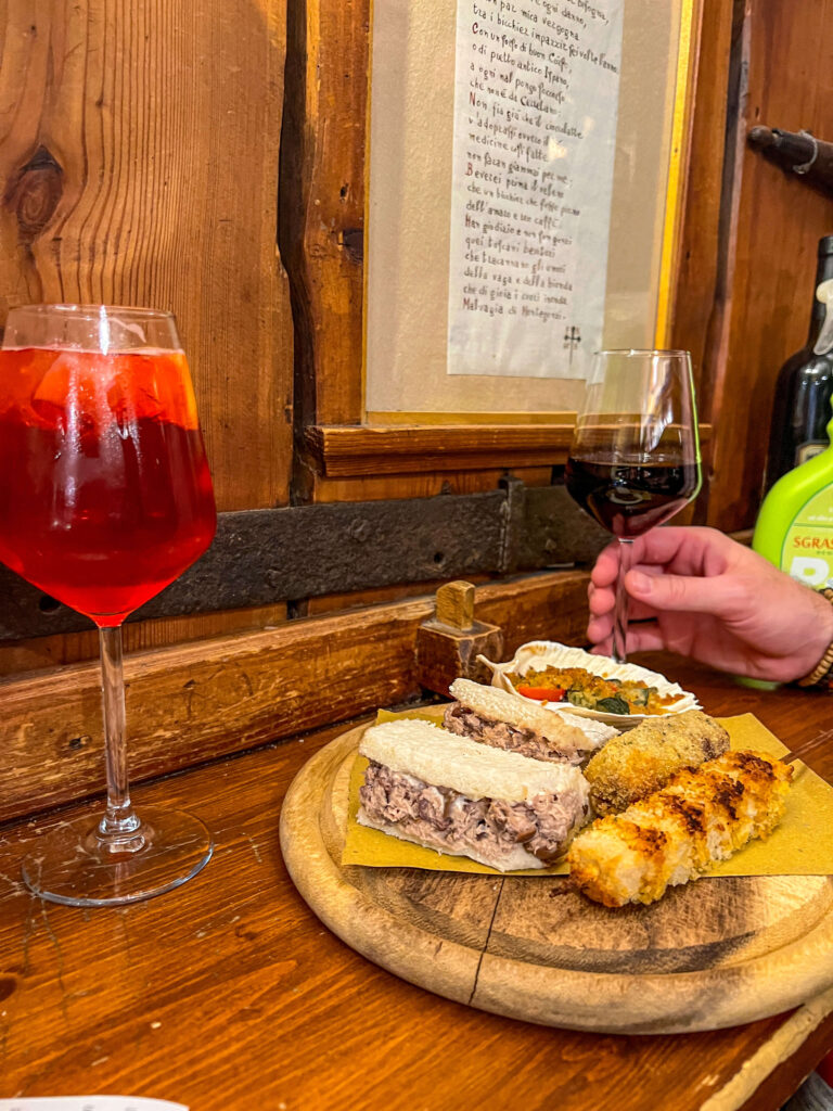 cicchetti on a plate with a spritz and glass of wine