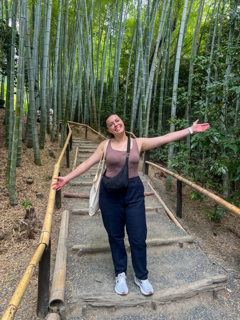 Kat smiling with her arms wide in the bamboo forest at Kodaiji temple in Kyoto