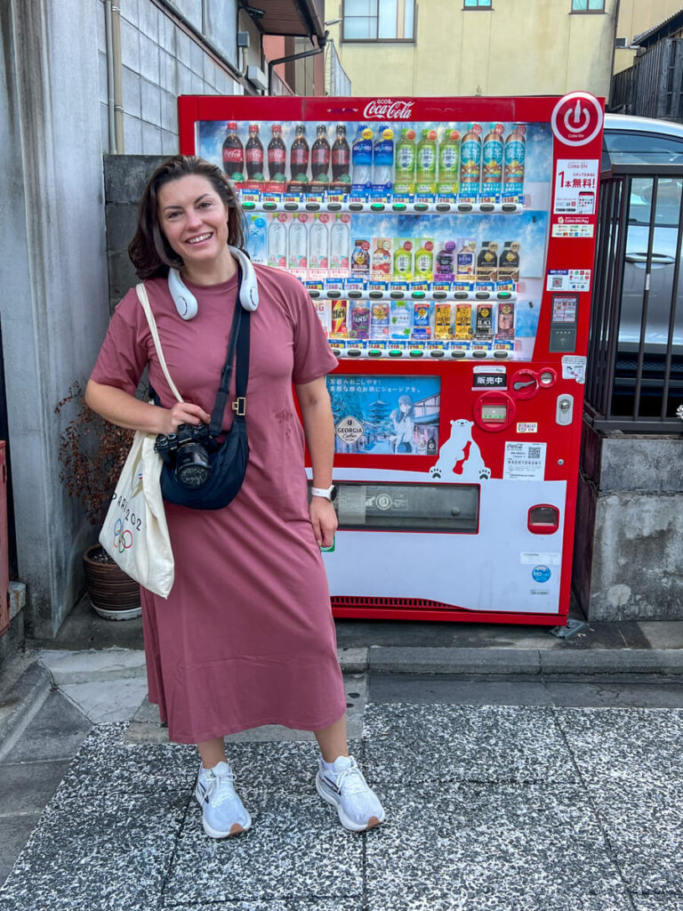 Kat wearing a neck fan in front of a vending machine